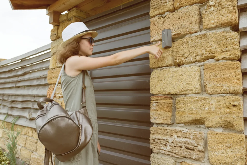 Femme actionnant la commande murale d’un volet roulant motorisé de couleur marron