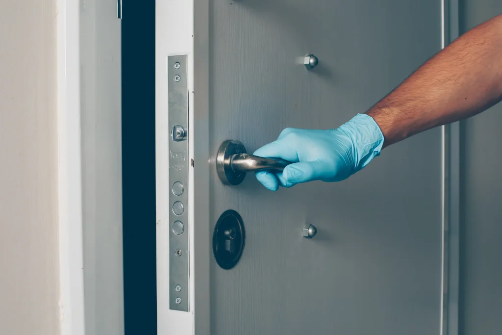 Main gantée ouvrant une porte d’entrée à serrure multipoints : dépannage et ouverture de porte
