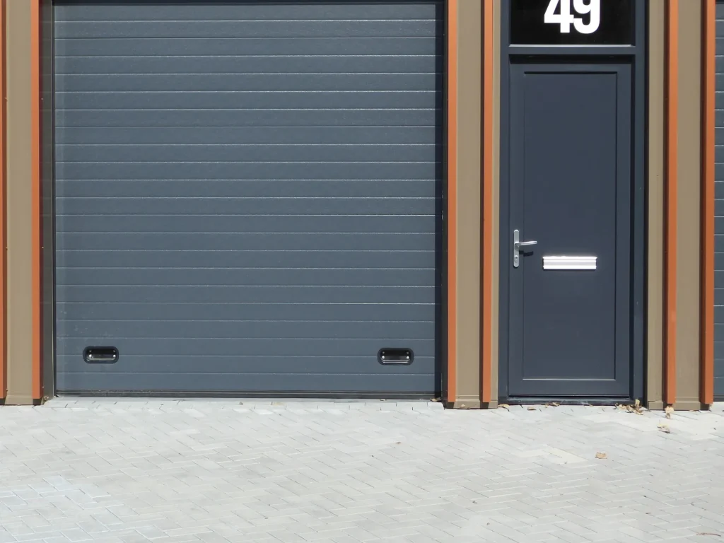 Porte de garage sectionnelle grise à côté d’une porte d’entrée – panne volet roulant