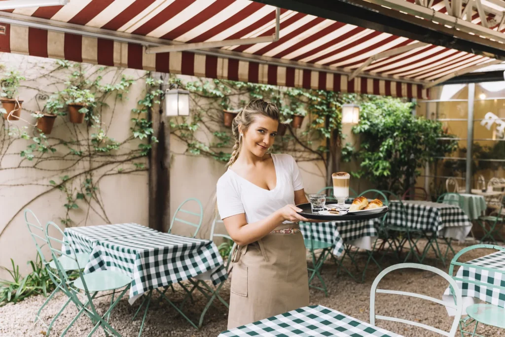 Terrasse de restaurant sous un grand store banne rayé rouge et blanc – installation store banne