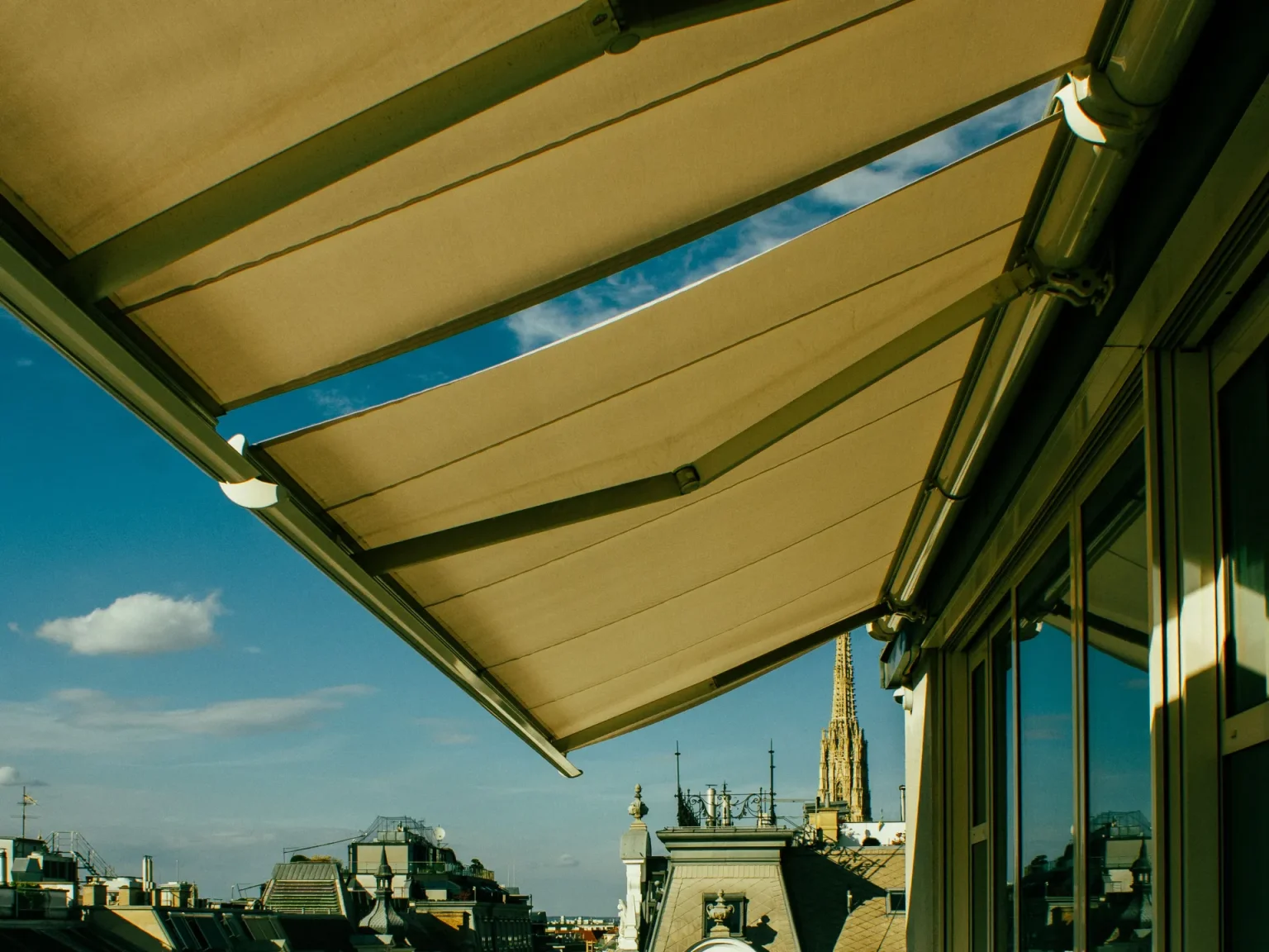 Grand store banne beige déployé au-dessus d’une terrasse en étage