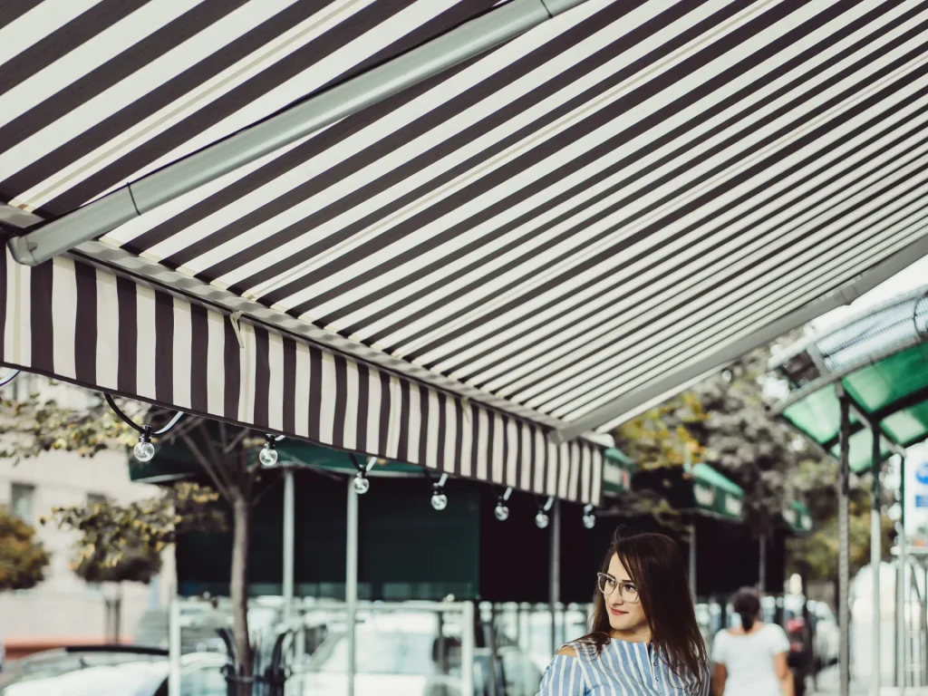 Terrasse de café protégée par un store banne rayé – stores extérieurs à Nice
