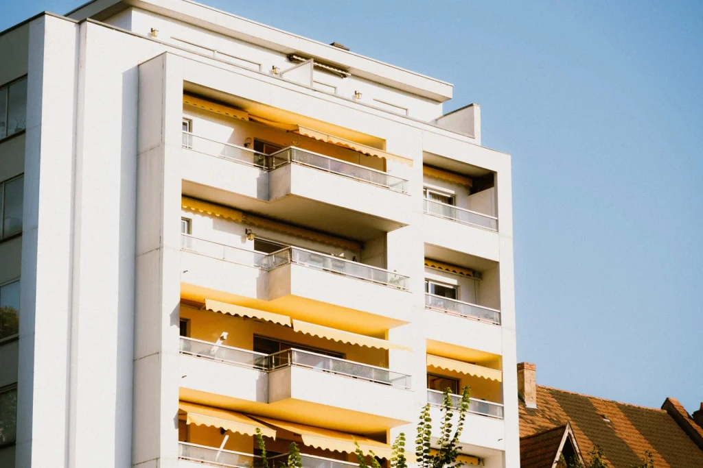 Stores bannes jaunes déployés sur les balcons d’un immeuble blanc – prix store banne